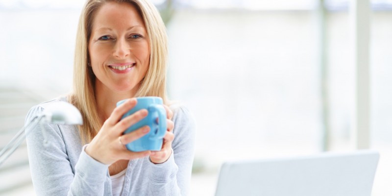 Portrait of mature business woman with a laptop and drinking cof